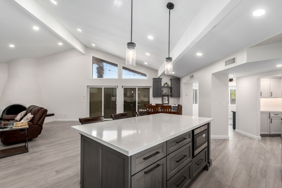 Inspiration for a mid-sized transitional porcelain tile and gray floor eat-in kitchen remodel in Phoenix with an undermount sink, shaker cabinets, gray cabinets, quartz countertops, white backsplash, subway tile backsplash, stainless steel appliances, an island and white countertops