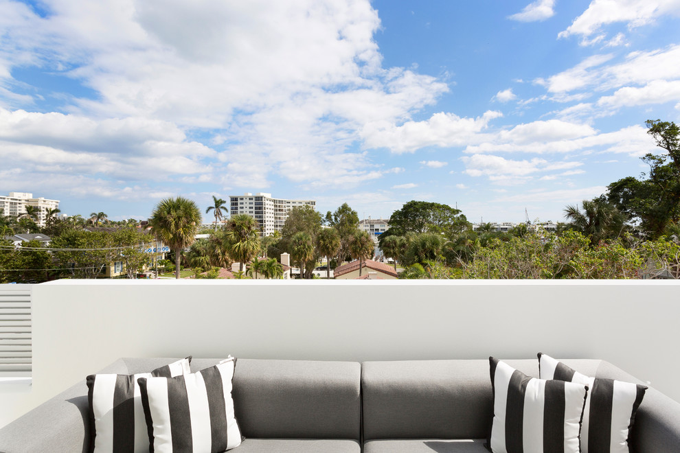 Photo of a mid-sized modern balcony in Miami with a roof extension and mixed railing.