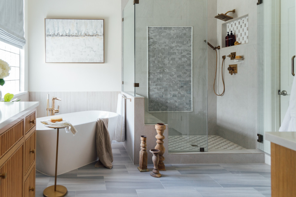 Свежая идея для дизайна: главная ванная комната в стиле неоклассика (современная классика) с светлыми деревянными фасадами, отдельно стоящей ванной, унитазом-моноблоком, керамогранитной плиткой, белыми стенами, полом из керамогранита, врезной раковиной, столешницей из искусственного кварца, душем с распашными дверями, белой столешницей, нишей, тумбой под две раковины и плоскими фасадами - отличное фото интерьера