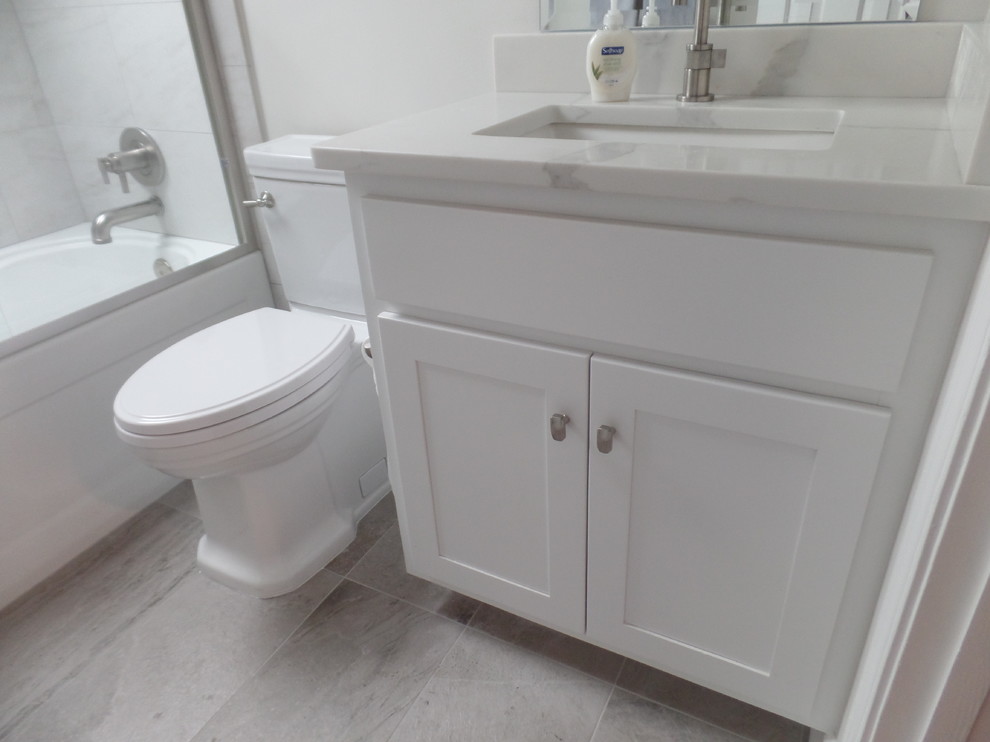 Mid-sized contemporary kids bathroom in Other with shaker cabinets, white cabinets, an alcove tub, a shower/bathtub combo, a two-piece toilet, gray tile, porcelain tile, grey walls, porcelain floors, an undermount sink, engineered quartz benchtops and grey floor.