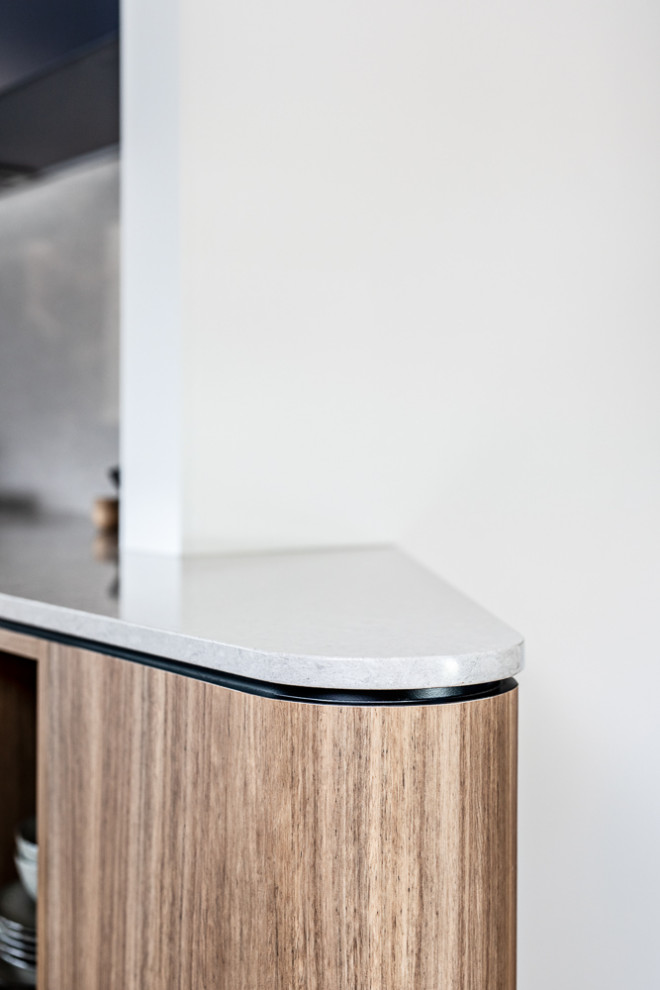 Photo of a mid-sized contemporary galley separate kitchen in Sydney with a double-bowl sink, brown cabinets, quartz benchtops, grey splashback, engineered quartz splashback, stainless steel appliances, medium hardwood floors, brown floor and grey benchtop.
