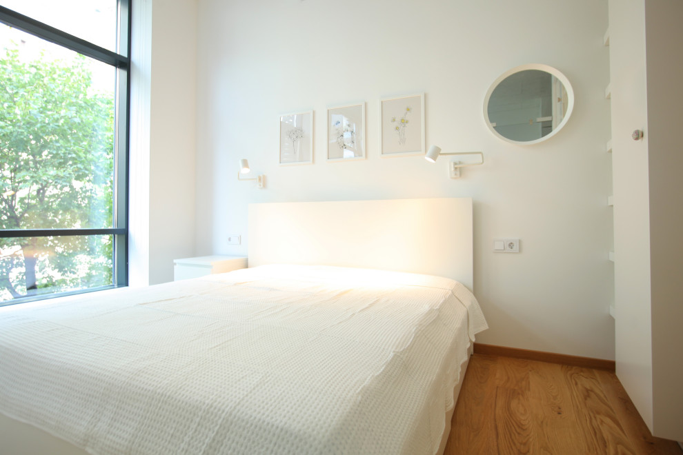 Imagen de dormitorio principal contemporáneo pequeño sin chimenea con paredes blancas, suelo laminado y suelo beige