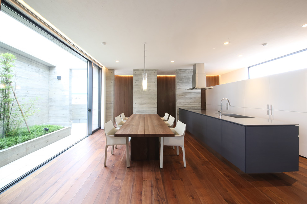 Modern galley open plan kitchen in Other with a single-bowl sink, medium hardwood floors, flat-panel cabinets, white cabinets, stainless steel benchtops, grey splashback, stone slab splashback and a peninsula.