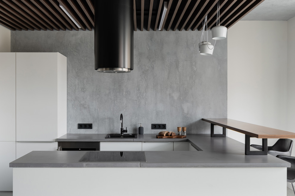 Contemporary u-shaped kitchen in Saint Petersburg with a drop-in sink, flat-panel cabinets, white cabinets, grey splashback, a peninsula and grey benchtop.