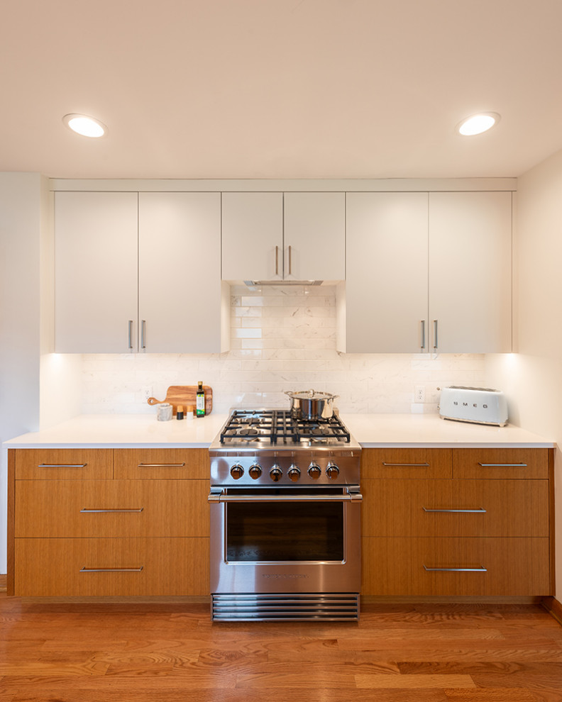 Foto på ett mellanstort 50 tals vit kök, med en enkel diskho, släta luckor, skåp i ljust trä, bänkskiva i kvarts, vitt stänkskydd, stänkskydd i keramik, rostfria vitvaror, mellanmörkt trägolv och brunt golv