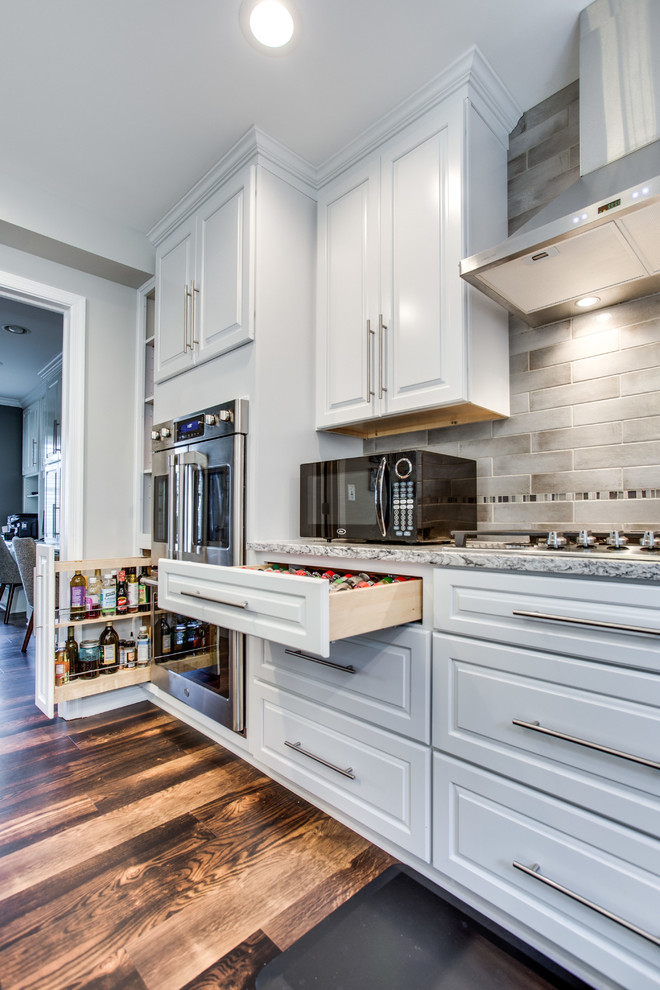 Inspiration for a large traditional u-shaped kitchen in DC Metro with an undermount sink, raised-panel cabinets, quartz benchtops, stainless steel appliances, dark hardwood floors and with island.
