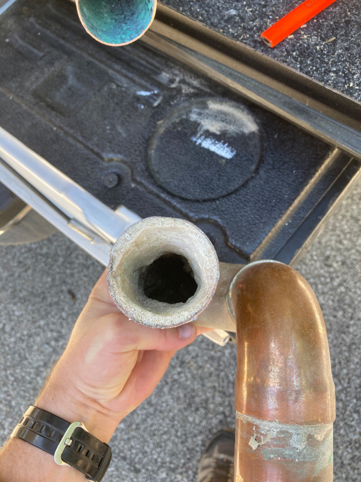 Plumber pushing to replace copper with PVC pipes in shower drain.
