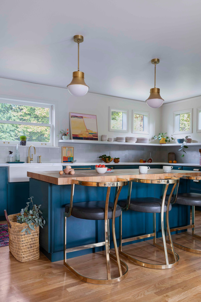 Inspiration for a mid-sized midcentury eat-in kitchen in Portland with a farmhouse sink, beaded inset cabinets, blue cabinets, quartzite benchtops, green splashback, ceramic splashback, stainless steel appliances, light hardwood floors, with island, beige floor and white benchtop.