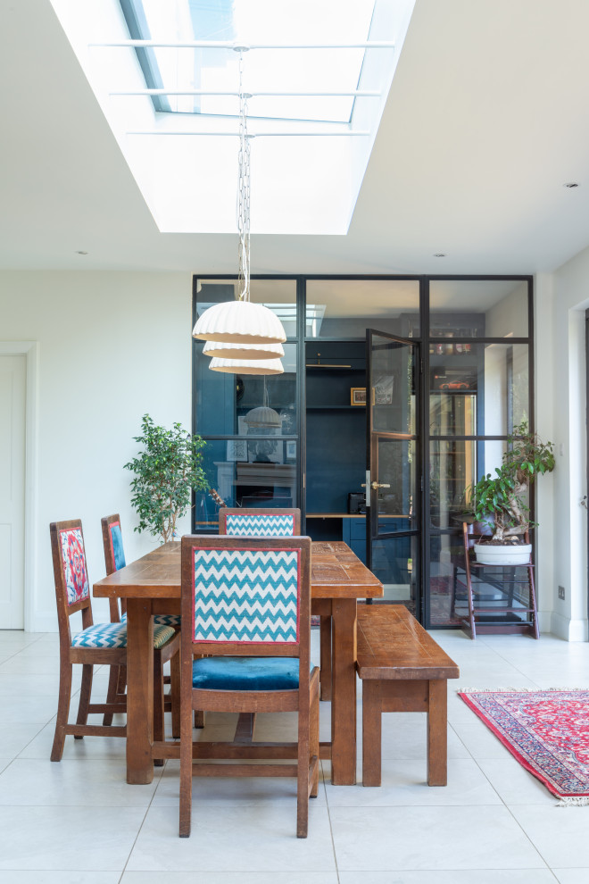 This is an example of a large eclectic open plan dining room in Hertfordshire with blue walls, porcelain flooring, beige floors and feature lighting.