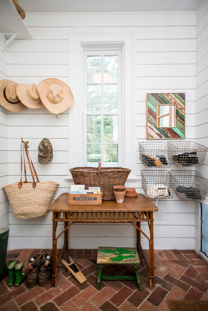 Design ideas for a small country mudroom in Charlotte with white walls and brick floors.