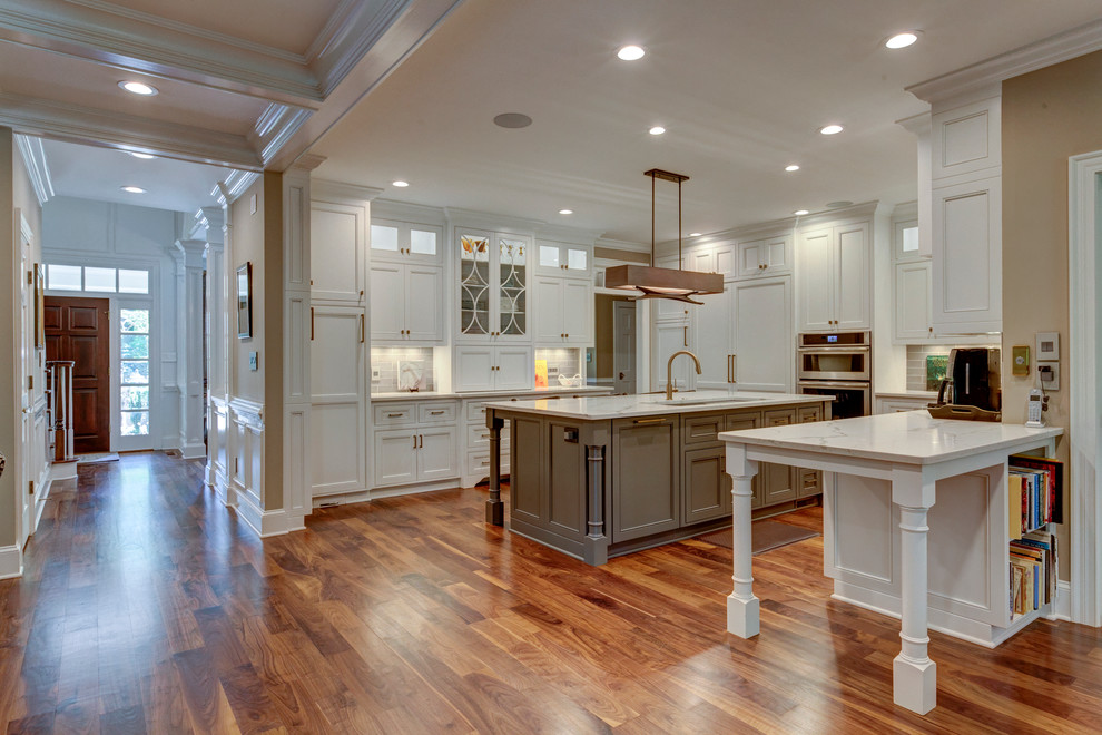 Design ideas for a large transitional u-shaped open plan kitchen in Raleigh with beaded inset cabinets, white cabinets, grey splashback, stainless steel appliances, dark hardwood floors, with island, a triple-bowl sink, marble benchtops and subway tile splashback.