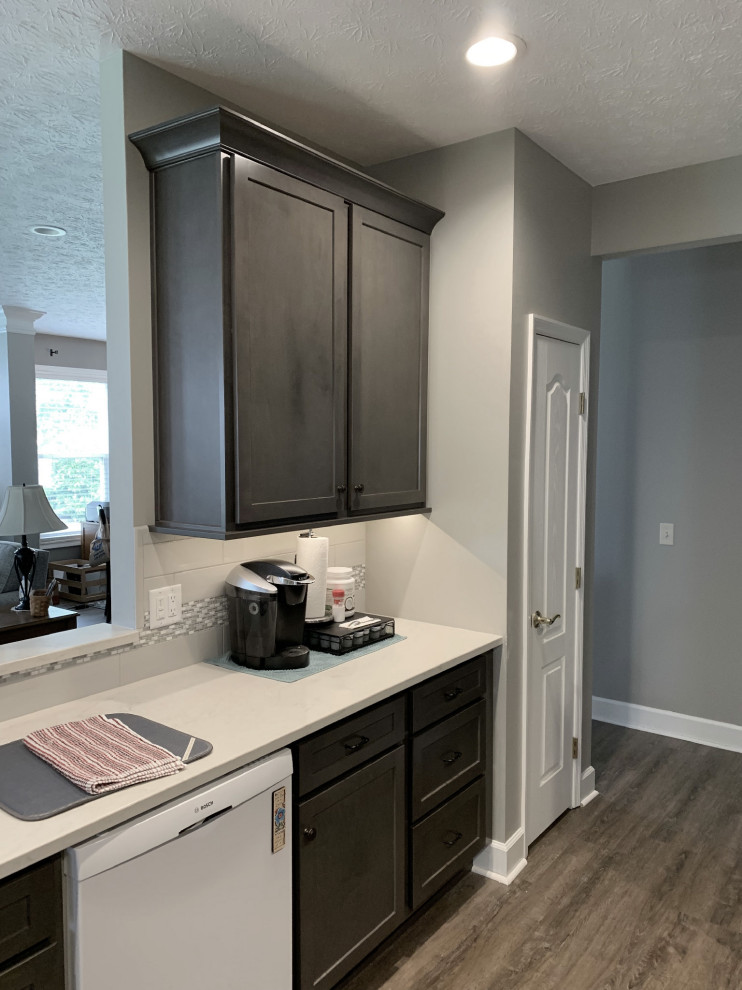 Open concept kitchen - large transitional u-shaped vinyl floor and gray floor open concept kitchen idea with an undermount sink, shaker cabinets, gray cabinets, quartz countertops, gray backsplash, ceramic backsplash, stainless steel appliances, a peninsula and white countertops