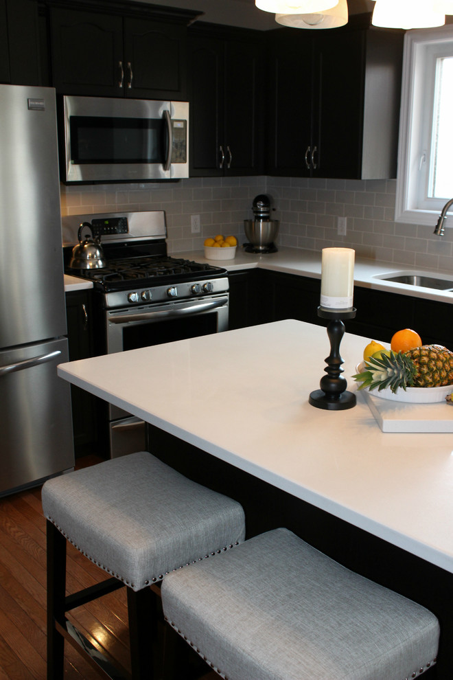 Example of a mid-sized transitional u-shaped medium tone wood floor open concept kitchen design in Toronto with an undermount sink, recessed-panel cabinets, dark wood cabinets, quartzite countertops, gray backsplash, subway tile backsplash, stainless steel appliances and an island