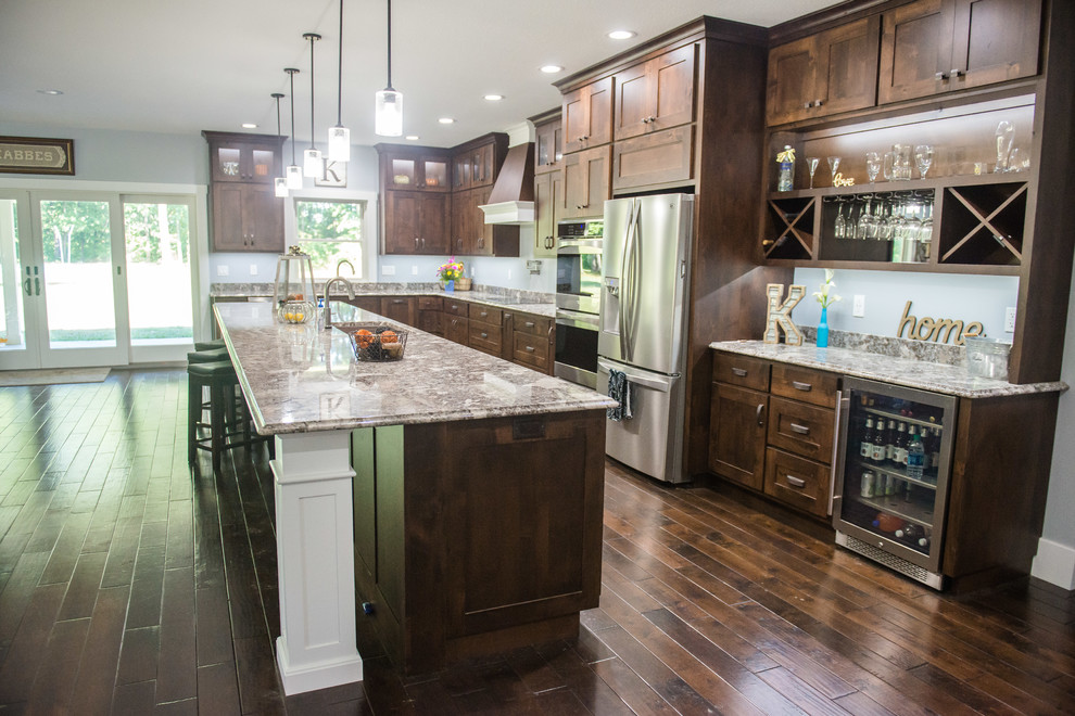 Transitional l-shaped open concept kitchen photo with an undermount sink, shaker cabinets, dark wood cabinets, granite countertops, stainless steel appliances, an island and multicolored countertops