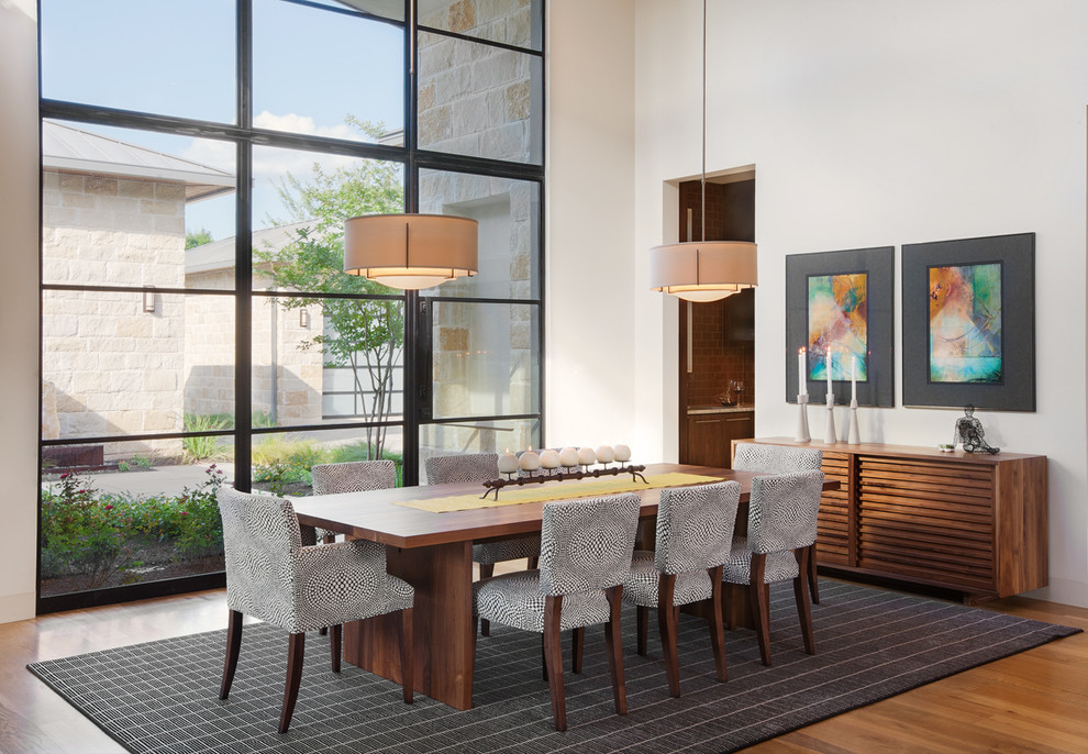 This is an example of a large contemporary separate dining room in Austin with white walls, medium hardwood floors, no fireplace and brown floor.