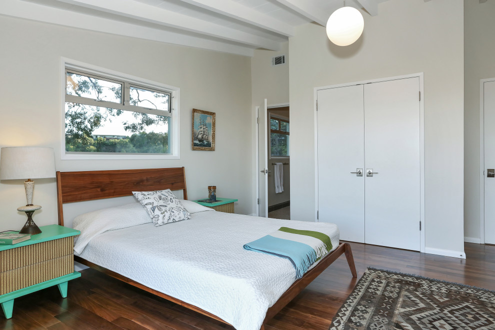 Midcentury bedroom in Los Angeles with beige walls, dark hardwood floors and brown floor.