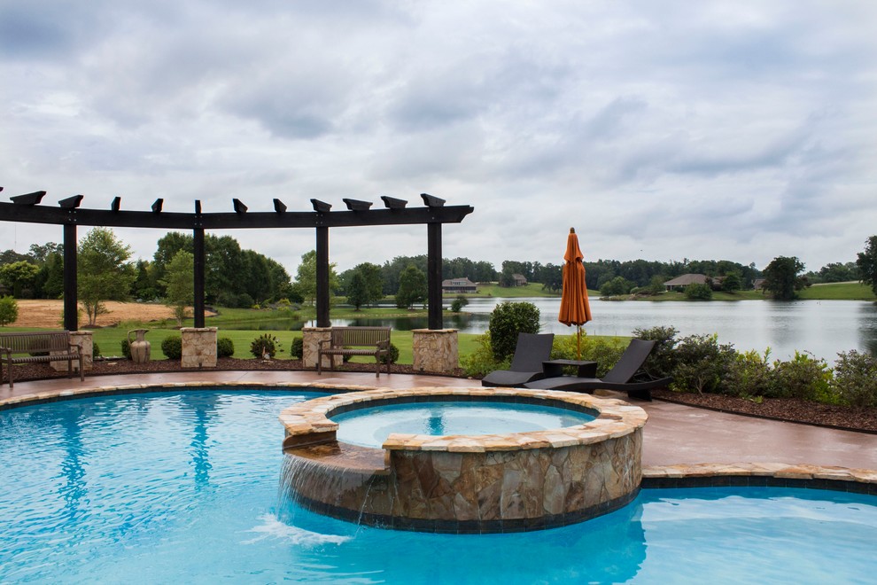 Example of a large transitional backyard custom-shaped and stone hot tub design