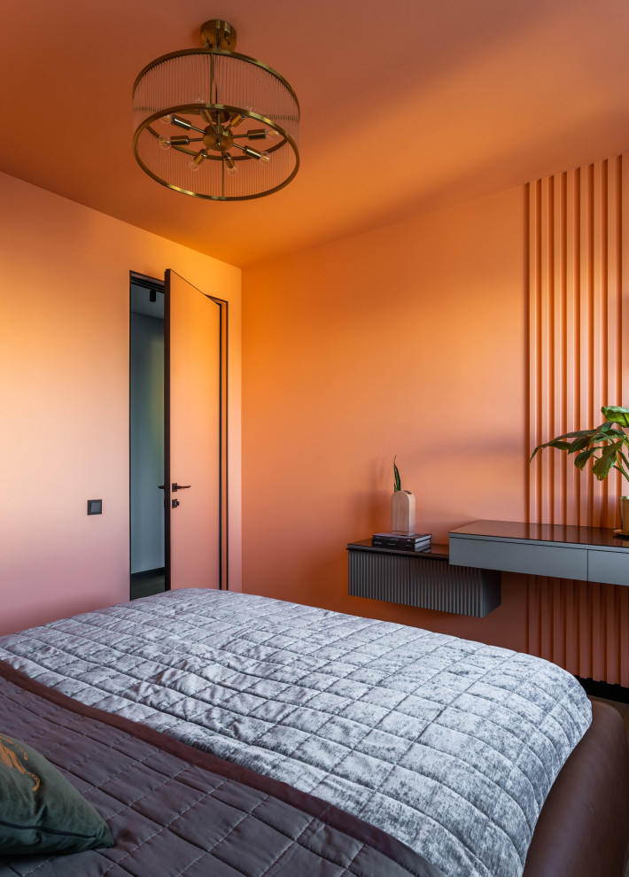 На фото: хозяйская спальня среднего размера в современном стиле с оранжевыми стенами, паркетным полом среднего тона и панелями на части стены с