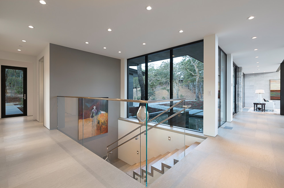 Expansive contemporary travertine u-shaped staircase in San Francisco with travertine risers and glass railing.