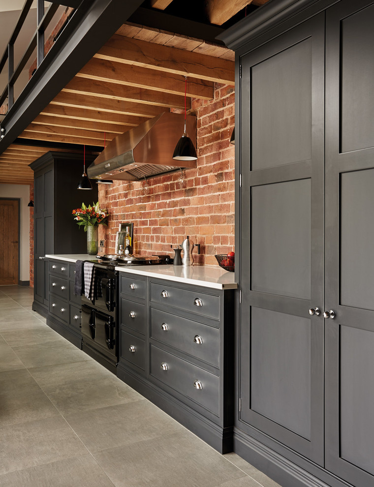 Photo of a large industrial open plan kitchen in Manchester with shaker cabinets, black cabinets, quartzite benchtops, with island and panelled appliances.
