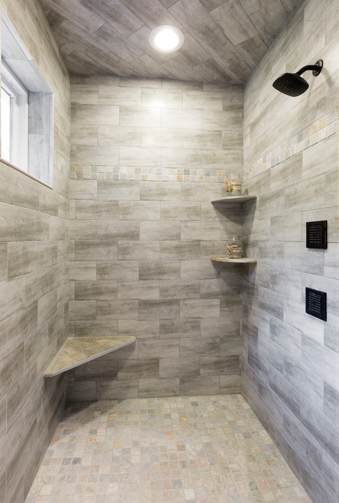 Photo of a large country master bathroom in Milwaukee with flat-panel cabinets, medium wood cabinets, a drop-in tub, a double shower, multi-coloured tile, ceramic tile, blue walls, ceramic floors, an undermount sink, marble benchtops, multi-coloured floor, a hinged shower door and white benchtops.