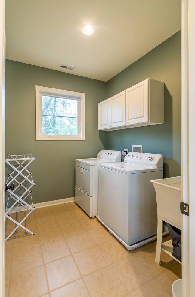 Photo of a small transitional single-wall laundry cupboard in Chicago with an utility sink, raised-panel cabinets, white cabinets, grey walls, ceramic floors, a side-by-side washer and dryer, beige floor, onyx benchtops, white benchtop, wallpaper and wallpaper.