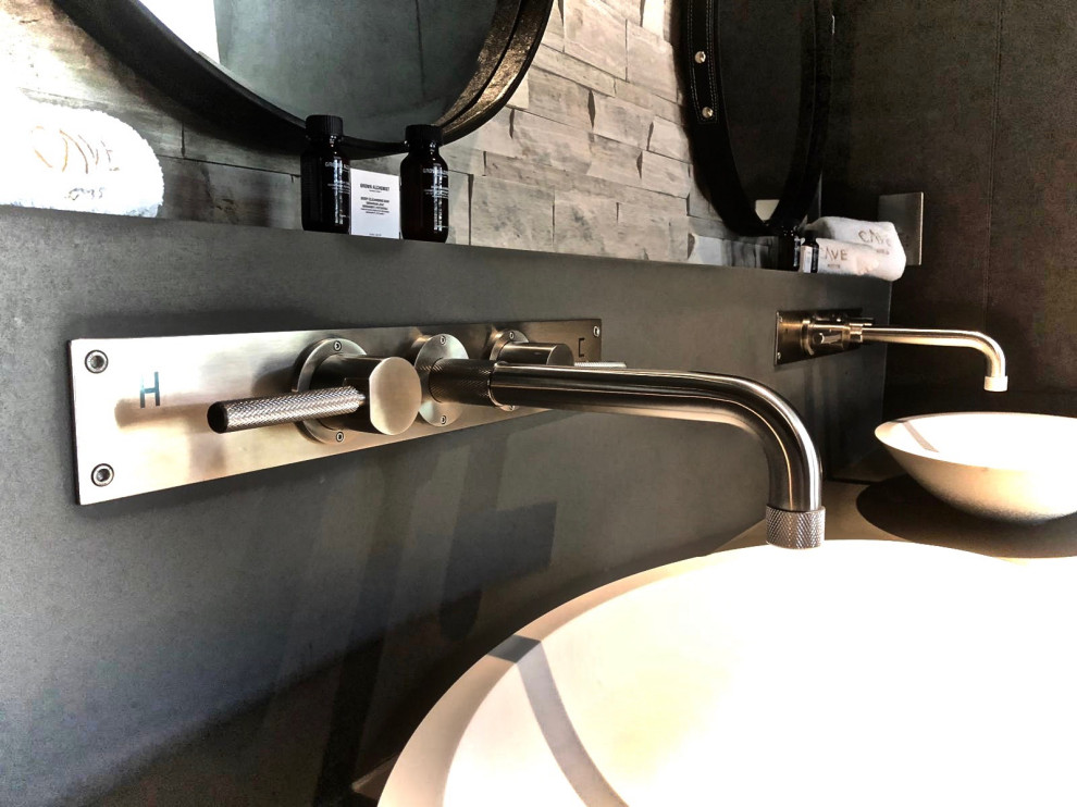 This is an example of a large modern grey and black ensuite wet room bathroom in Kent with flat-panel cabinets, medium wood cabinets, a freestanding bath, a wall mounted toilet, grey tiles, porcelain tiles, grey walls, medium hardwood flooring, a vessel sink, marble worktops, beige floors, a hinged door, grey worktops, feature lighting, double sinks, a floating vanity unit and wallpapered walls.