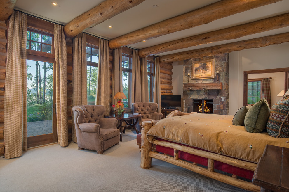 Photo of a country bedroom in Other with white walls, carpet, a standard fireplace, a stone fireplace surround and beige floor.