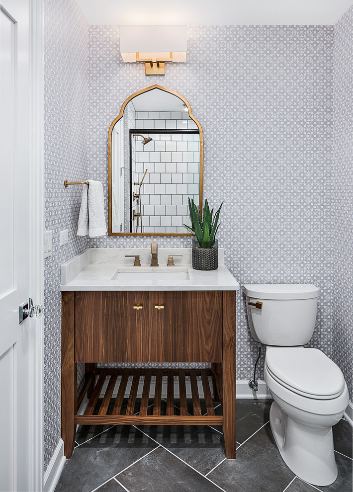 This is an example of a transitional powder room in Chicago with furniture-like cabinets, dark wood cabinets, a two-piece toilet, grey walls, an undermount sink and grey floor.