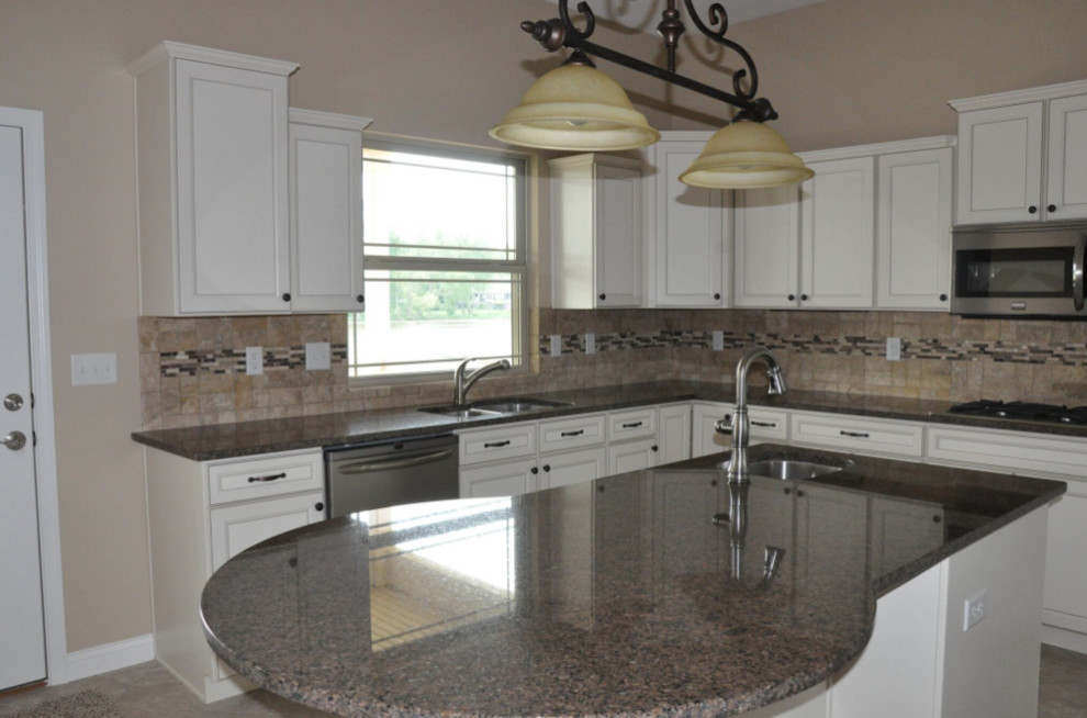 Mid-sized elegant l-shaped travertine floor and beige floor enclosed kitchen photo with a double-bowl sink, recessed-panel cabinets, white cabinets, granite countertops, beige backsplash, stone tile backsplash, stainless steel appliances and an island