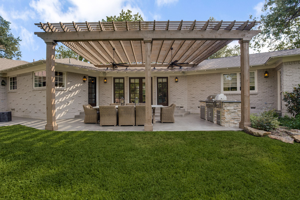 Design ideas for a mid-sized transitional backyard verandah in Dallas with an outdoor kitchen, concrete slab and a pergola.