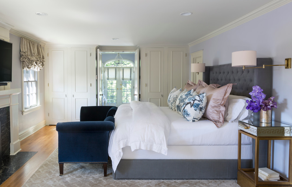 Inspiration for a mid-sized transitional master bedroom in Denver with purple walls, light hardwood floors, a standard fireplace, a stone fireplace surround and beige floor.