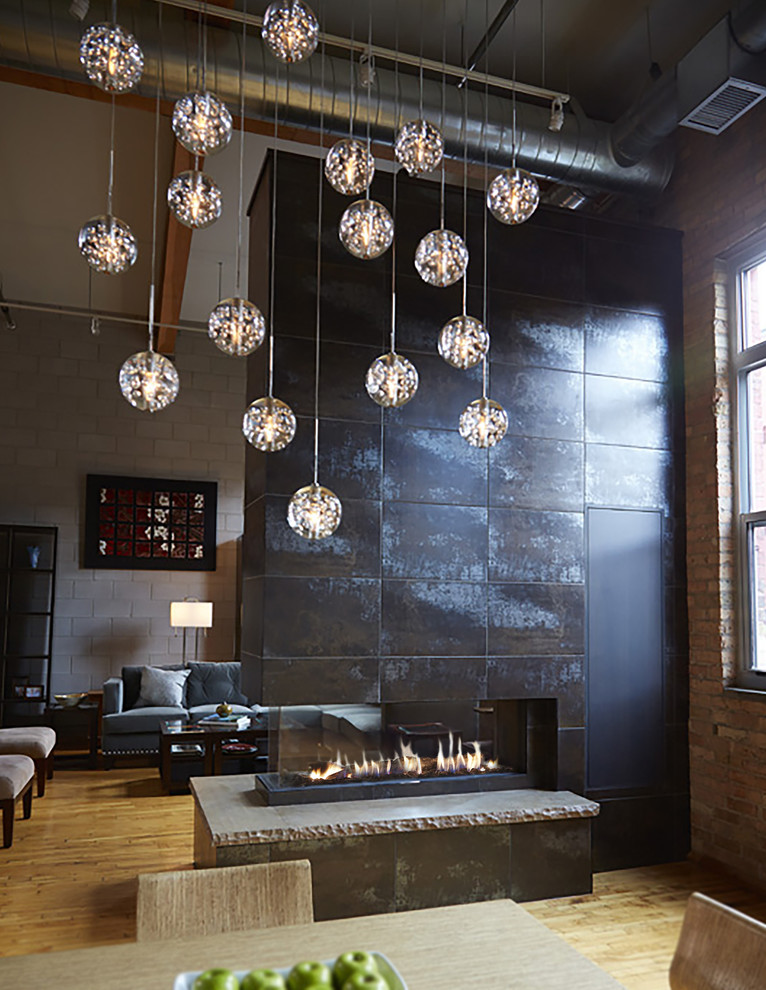 Photo of a mid-sized industrial loft-style family room in Minneapolis with light hardwood floors, a two-sided fireplace, a metal fireplace surround, no tv and brown floor.