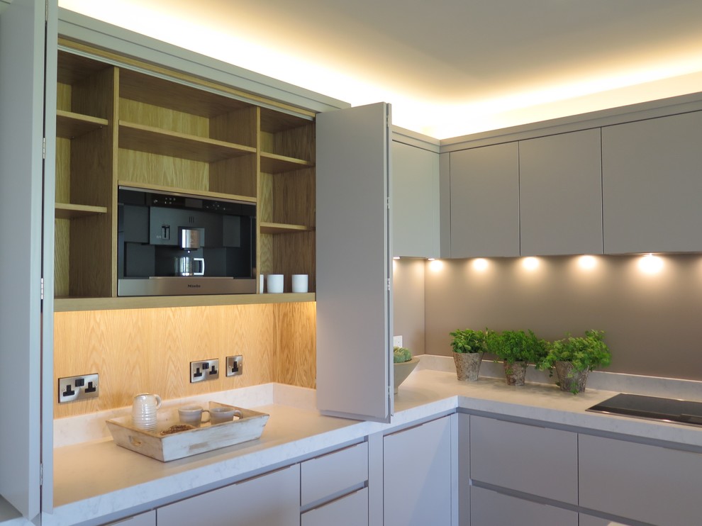 Inspiration for an expansive contemporary open plan kitchen in Cheshire with a double-bowl sink, flat-panel cabinets, grey cabinets, quartzite benchtops, grey splashback, glass sheet splashback, stainless steel appliances, porcelain floors and multiple islands.