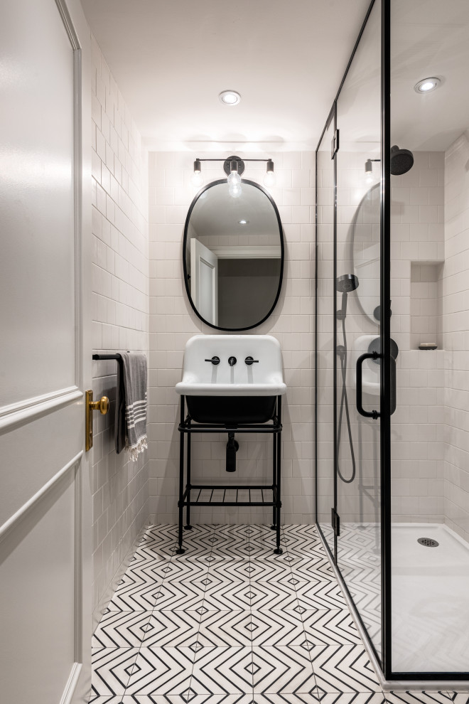 Bathroom in New York with a corner shower, white tile, ceramic tile, concrete floors, a pedestal sink, white floor, a hinged shower door, a single vanity and a freestanding vanity.