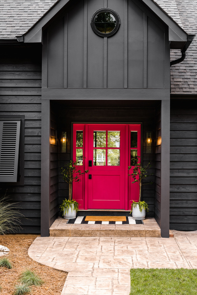 Imagen de puerta principal marinera de tamaño medio con paredes negras, suelo de cemento, puerta tipo holandesa, puerta roja, suelo beige y machihembrado