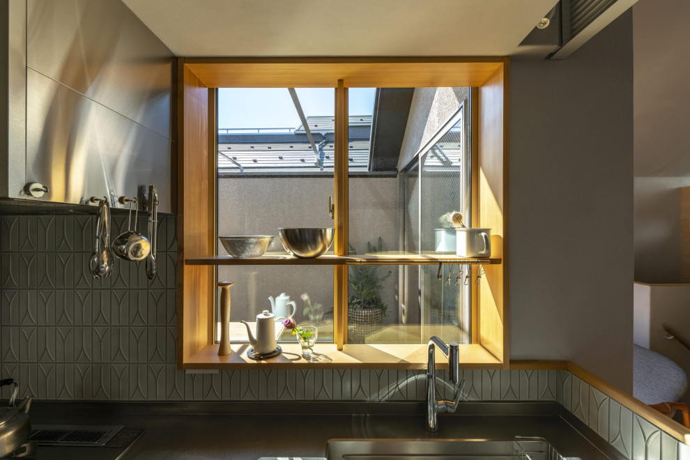 Bild på ett avskilt, litet minimalistiskt brun linjärt brunt kök, med en integrerad diskho, luckor med infälld panel, skåp i mellenmörkt trä, bänkskiva i rostfritt stål, grått stänkskydd, stänkskydd i keramik, rostfria vitvaror, plywoodgolv och brunt golv