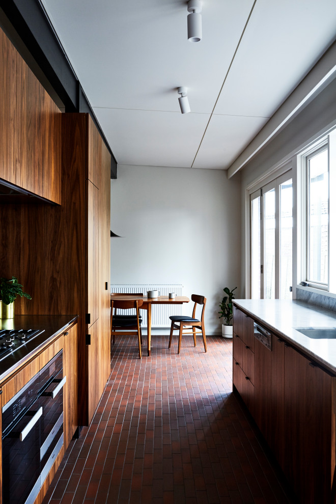 This is an example of a midcentury kitchen in Melbourne with marble benchtops, brick floors, red floor and yellow benchtop.
