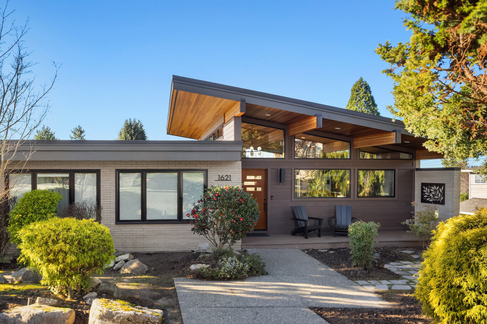 Large 1960s brown two-story house exterior idea in Seattle with a shed roof, a mixed material roof and a brown roof