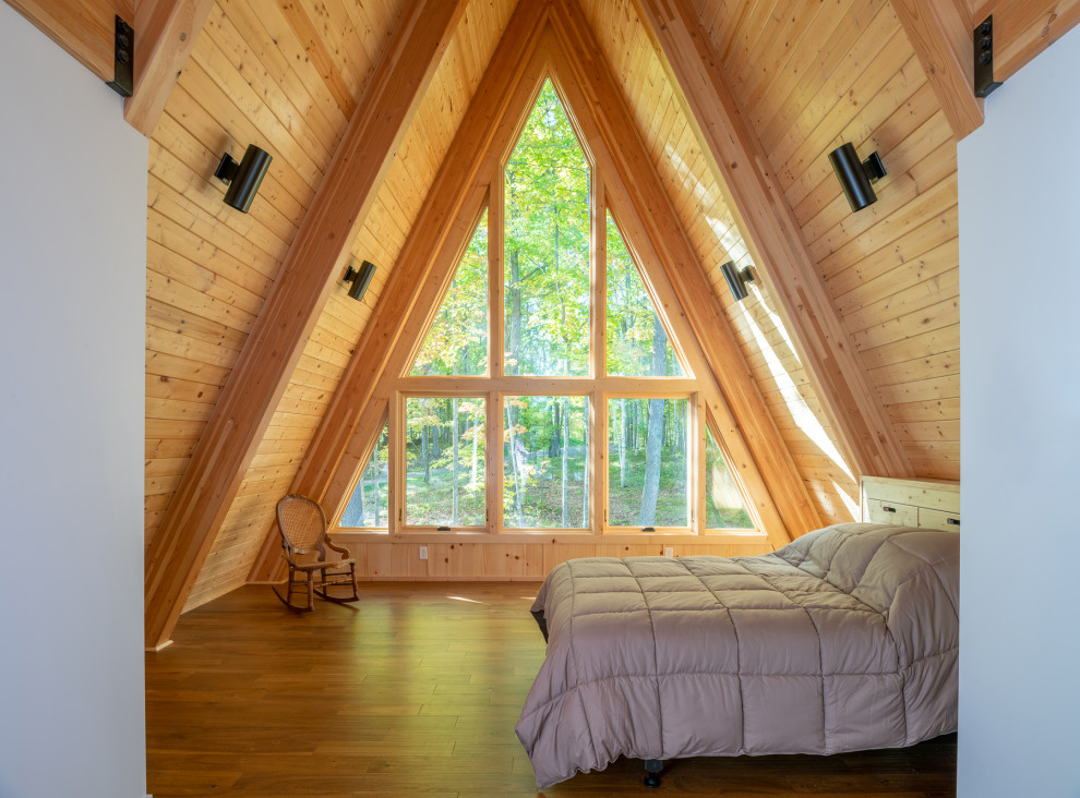Kleines Modernes Schlafzimmer im Loft-Style mit brauner Wandfarbe, braunem Holzboden, braunem Boden, freigelegten Dachbalken und Holzwänden in Minneapolis