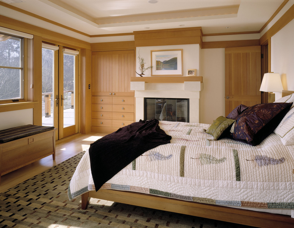 Photo of a large contemporary master bedroom in Seattle with beige walls, medium hardwood floors, a standard fireplace and beige floor.