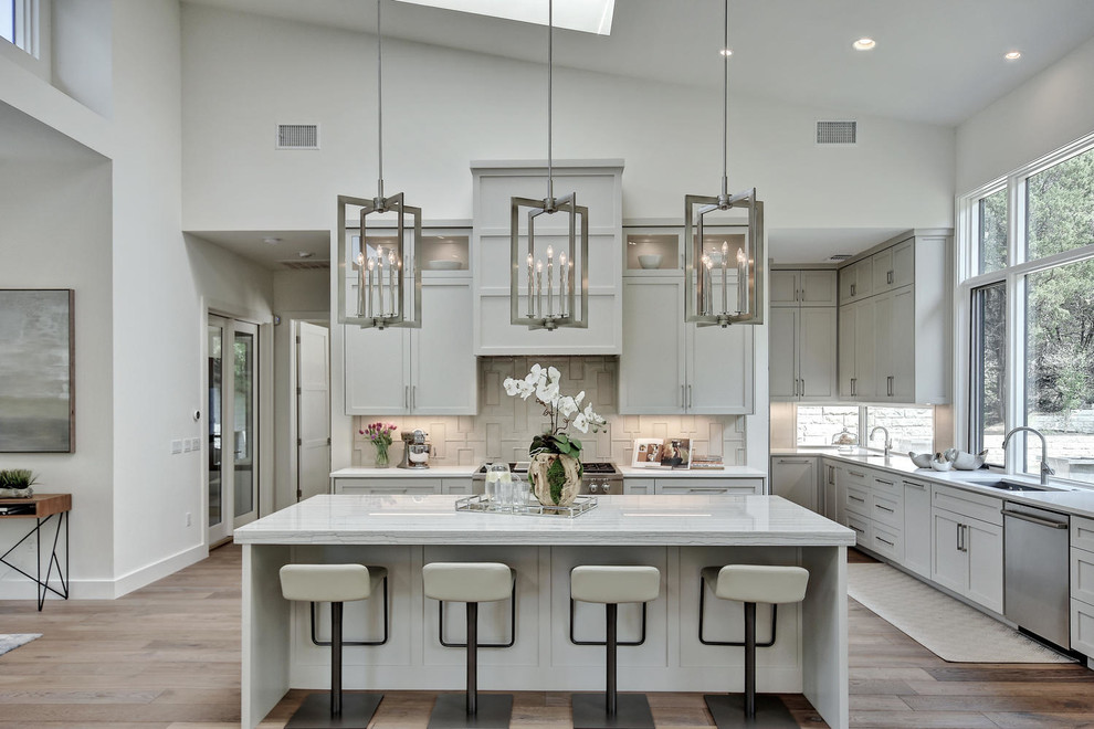 Inspiration for a transitional open plan kitchen in Austin with an undermount sink, shaker cabinets, grey cabinets, grey splashback, stainless steel appliances, light hardwood floors and with island.