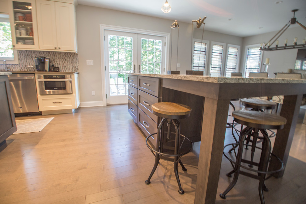 Example of a mid-sized transitional l-shaped dark wood floor eat-in kitchen design in New York with an undermount sink, recessed-panel cabinets, beige cabinets, quartz countertops, multicolored backsplash, subway tile backsplash, stainless steel appliances and two islands