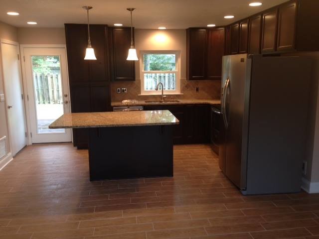 Inspiration for a transitional medium tone wood floor kitchen remodel in Jacksonville with dark wood cabinets, stainless steel appliances, an island, a double-bowl sink, granite countertops and beige backsplash