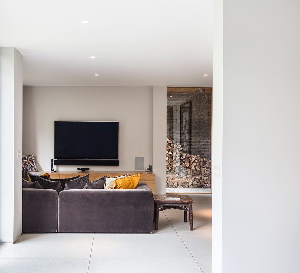Large traditional formal enclosed living room in London with grey walls, laminate floors, a standard fireplace, a stone fireplace surround, a wall-mounted tv and brown floor.