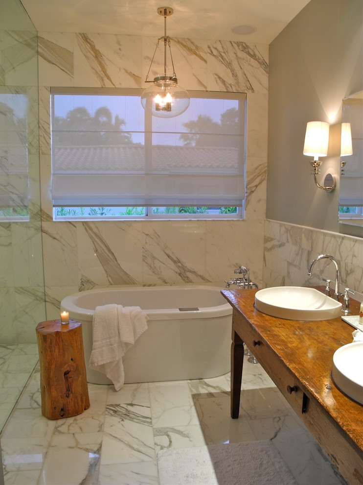 Photo of a contemporary bathroom in Miami with a vessel sink, medium wood cabinets, wood benchtops, a freestanding tub, white tile, brown benchtops and flat-panel cabinets.