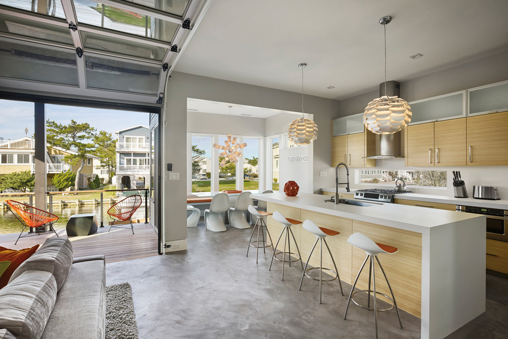 Large contemporary galley open plan kitchen in Other with flat-panel cabinets, light wood cabinets, stainless steel appliances, concrete floors, with island, grey floor, an undermount sink and window splashback.