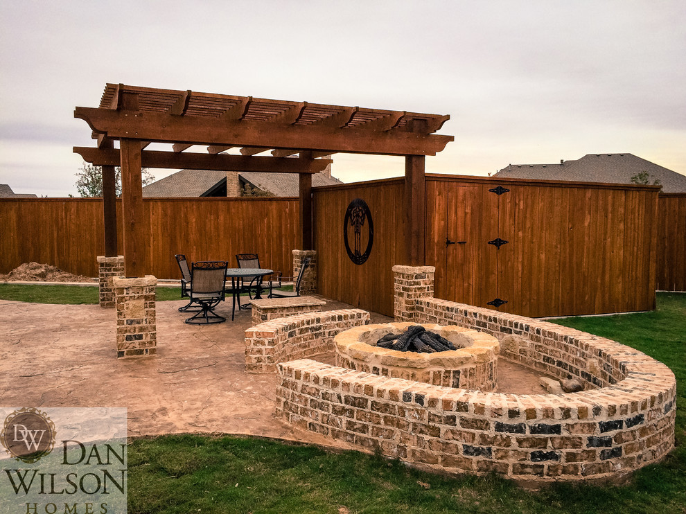 Large traditional backyard patio in Austin with a fire feature, stamped concrete and a pergola.