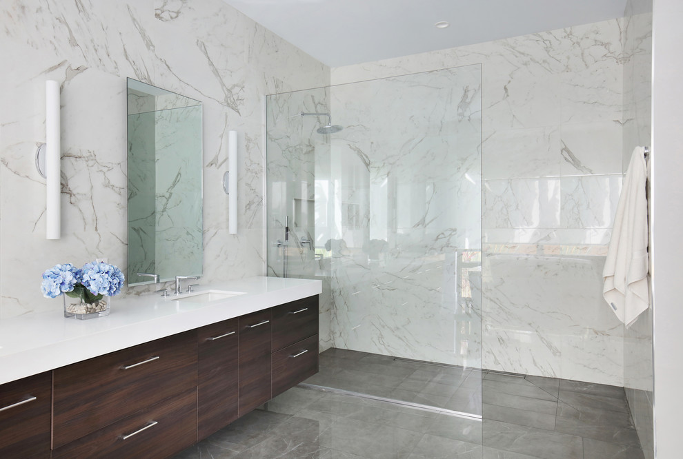 This is an example of a mid-sized modern master bathroom in Tampa with flat-panel cabinets, dark wood cabinets, a freestanding tub, a curbless shower, a two-piece toilet, white tile, porcelain tile, white walls, porcelain floors, an undermount sink, engineered quartz benchtops, grey floor, an open shower and white benchtops.
