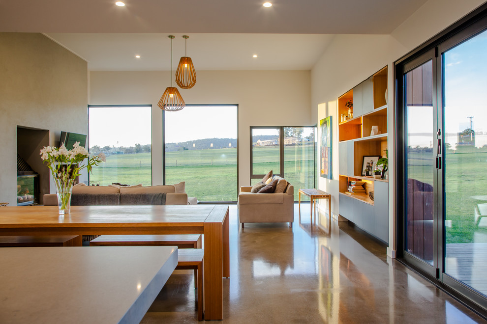 Photo of a mid-sized contemporary open concept living room in Hobart with white walls, concrete floors, a concrete fireplace surround and a wall-mounted tv.